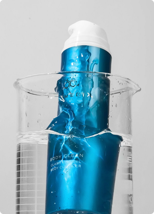 Body Clean Clarifying Gel body cleanser in a half-full glass beaker against light gray background. 